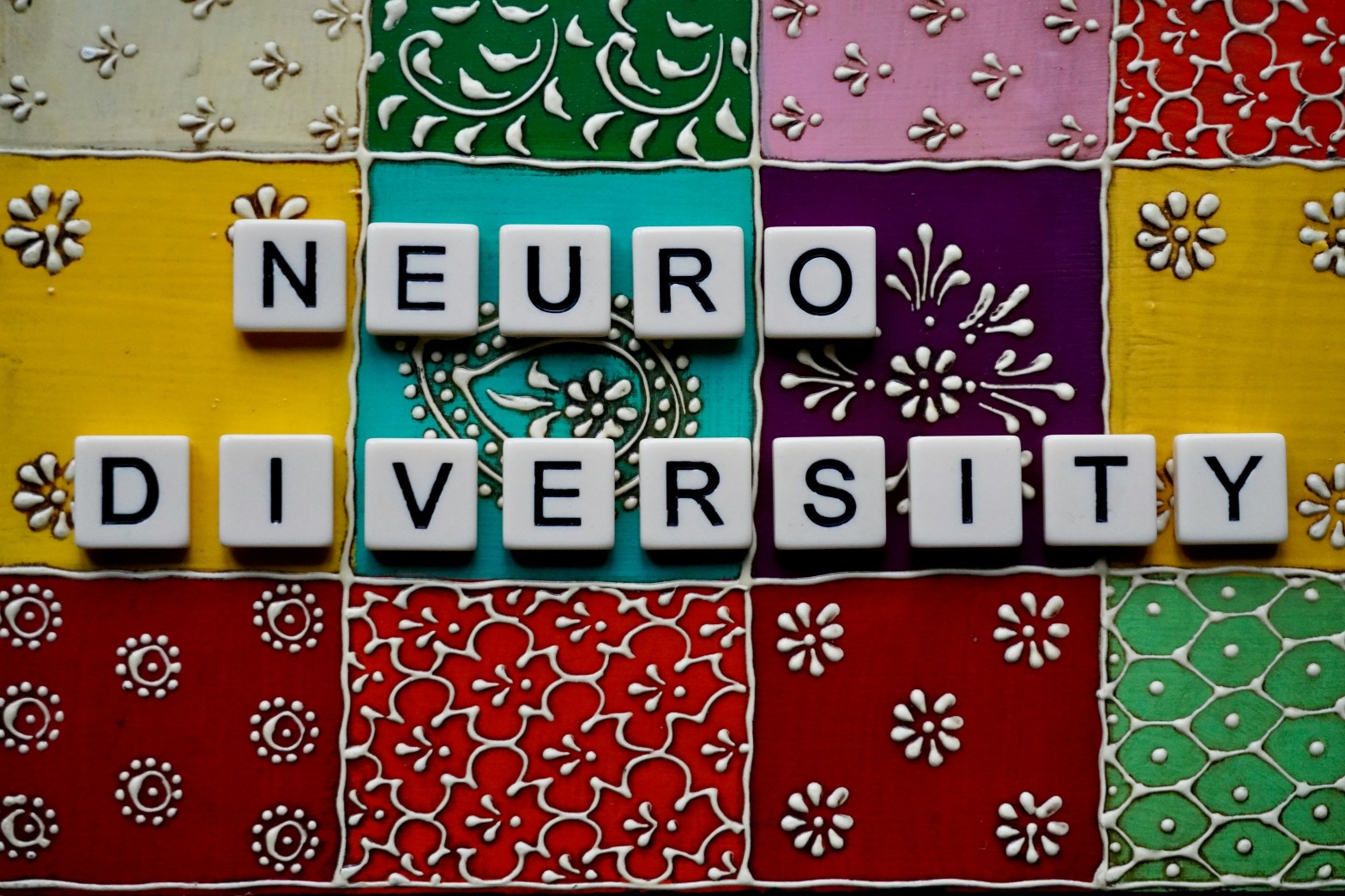 neurodiversity using scrabble tiles on top of bright pattern ceramic tiles.